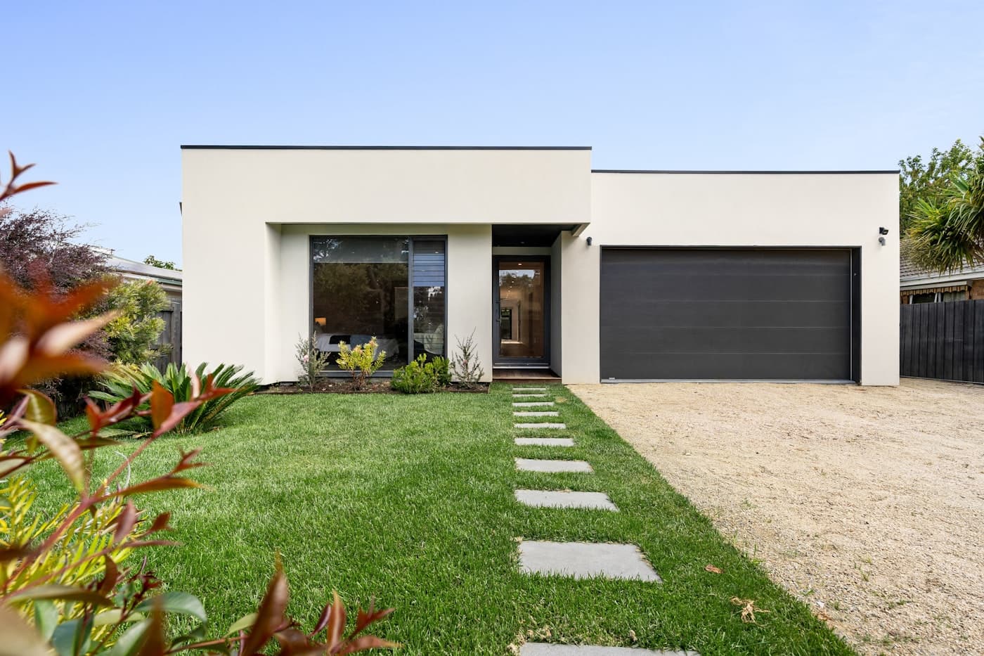 Modern home with a wide charcoal sectional garage door and manicured landscaping