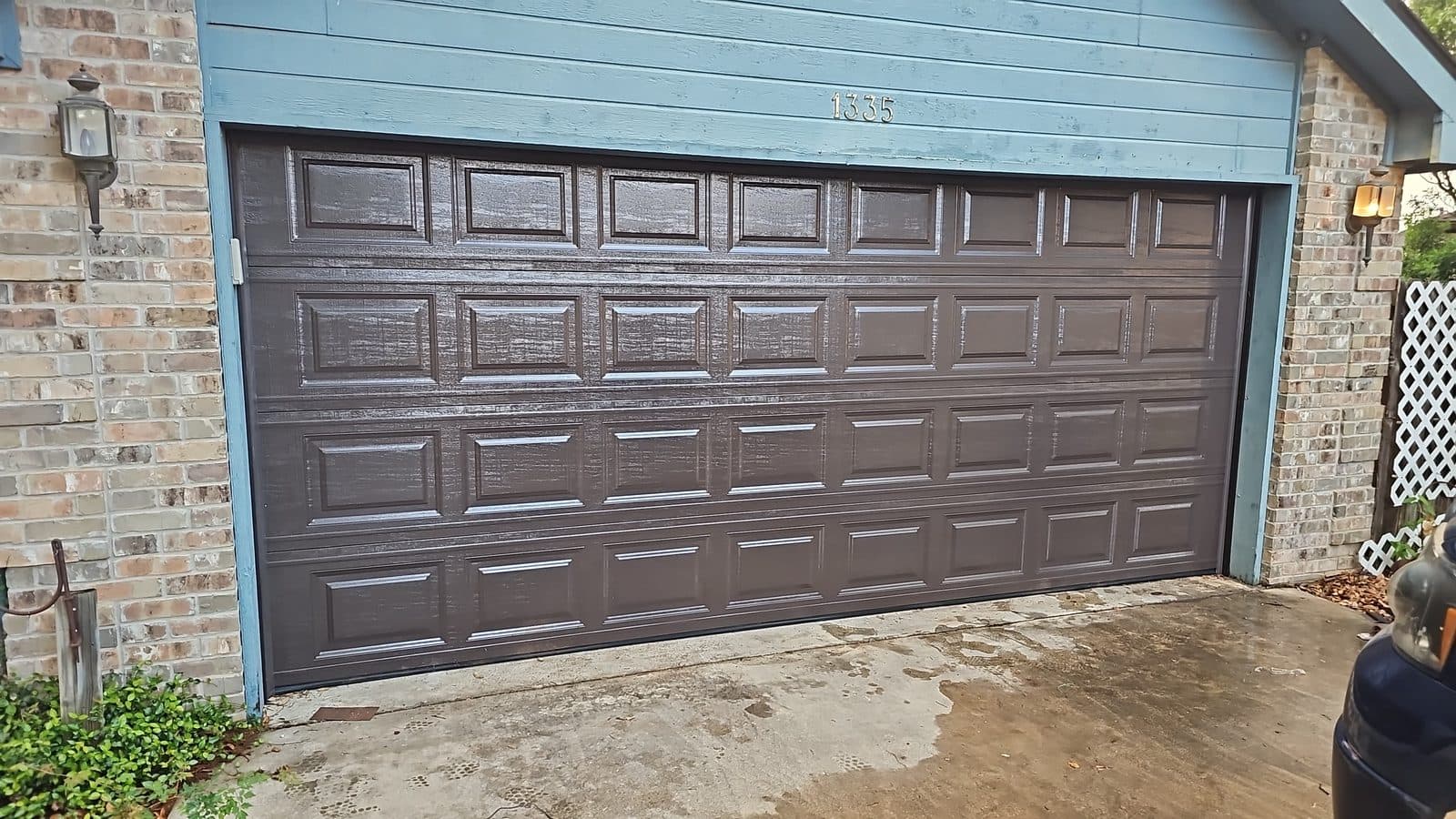 Freshly finished dark espresso short-panel garage door on a San Antonio brick home