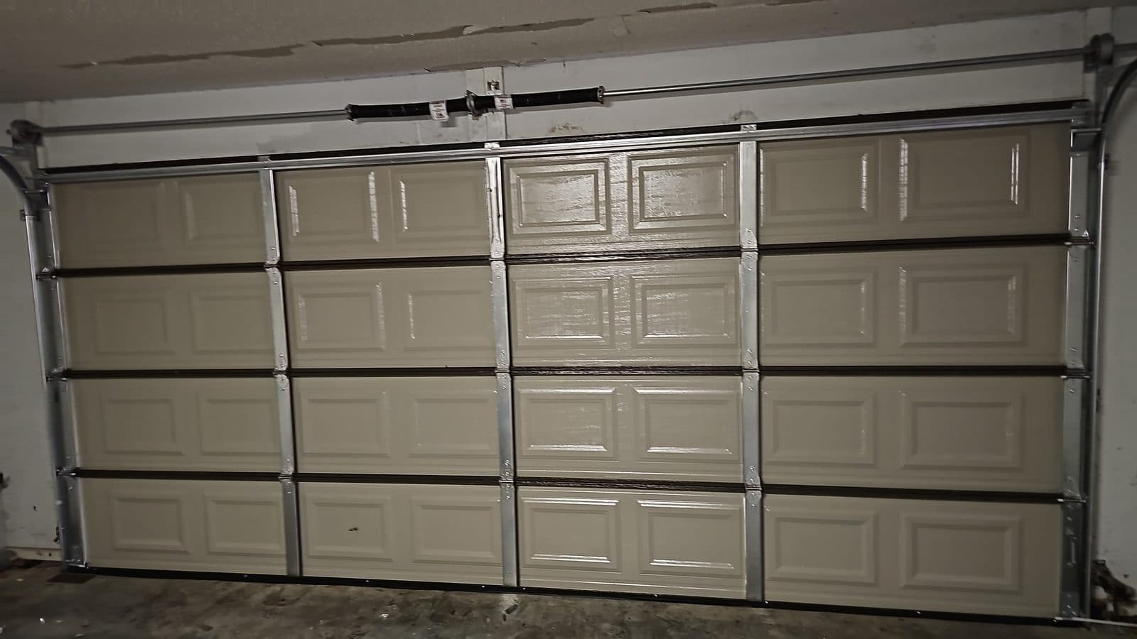Interior view of a two-car garage door with new tracks, rollers and torsion spring