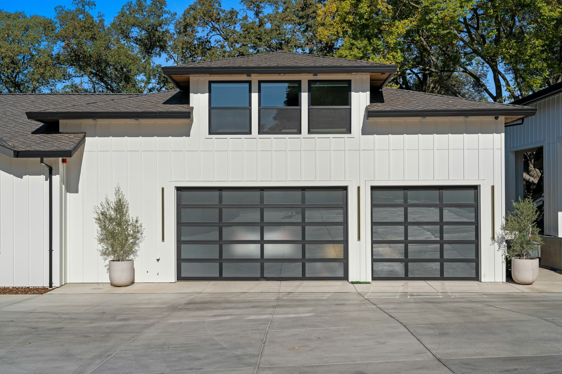 Modern white home with two flush glass-panel garage doors and a clean driveway